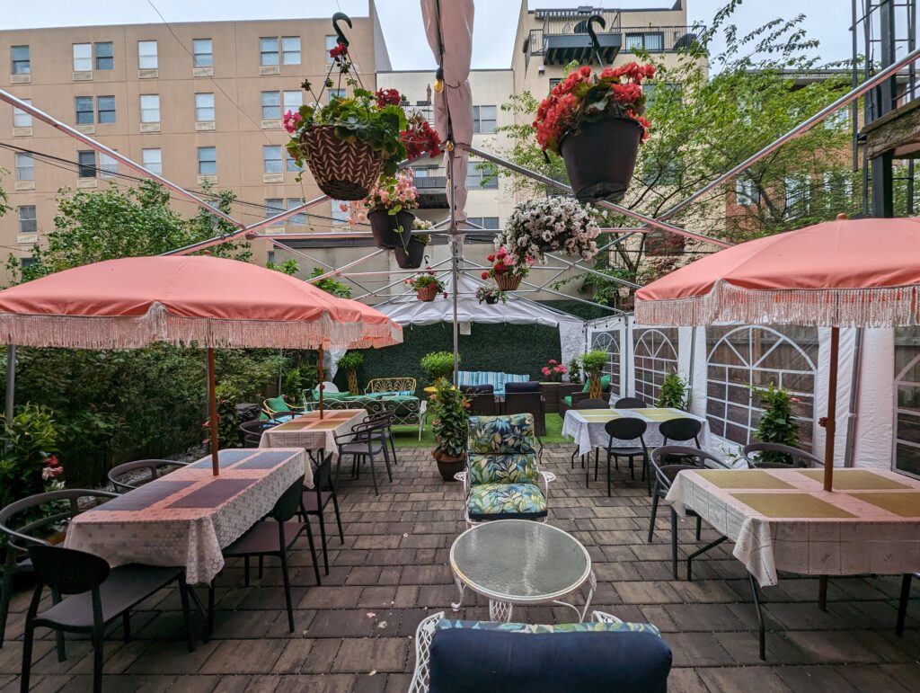 Courtyard with tables and chairs. Tables have red umbrellas