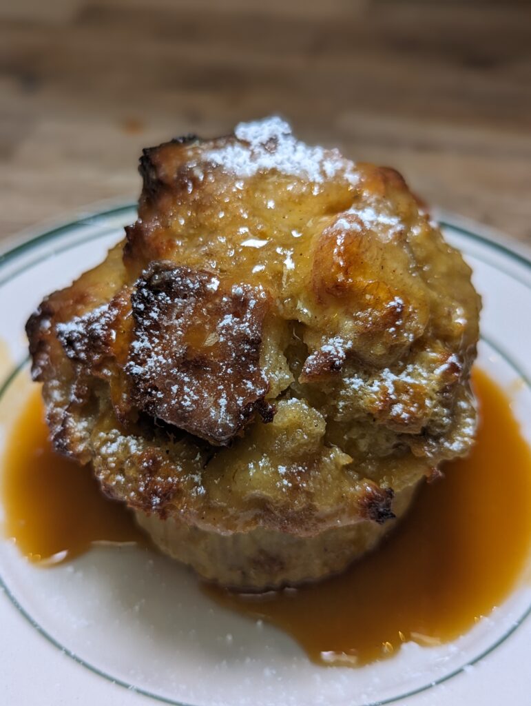 powdered sugar on top of a portion of bread pudding drizzled with sauce