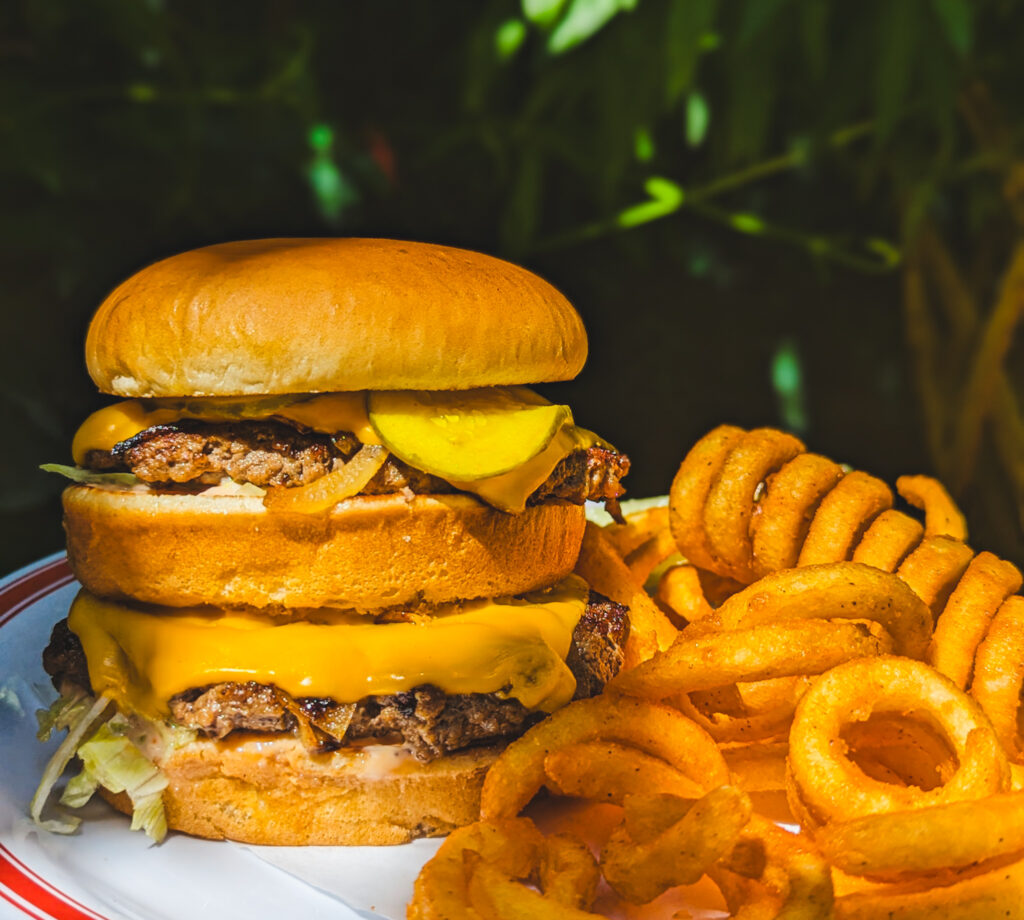 Double decker cheeseburger close up with curly fries